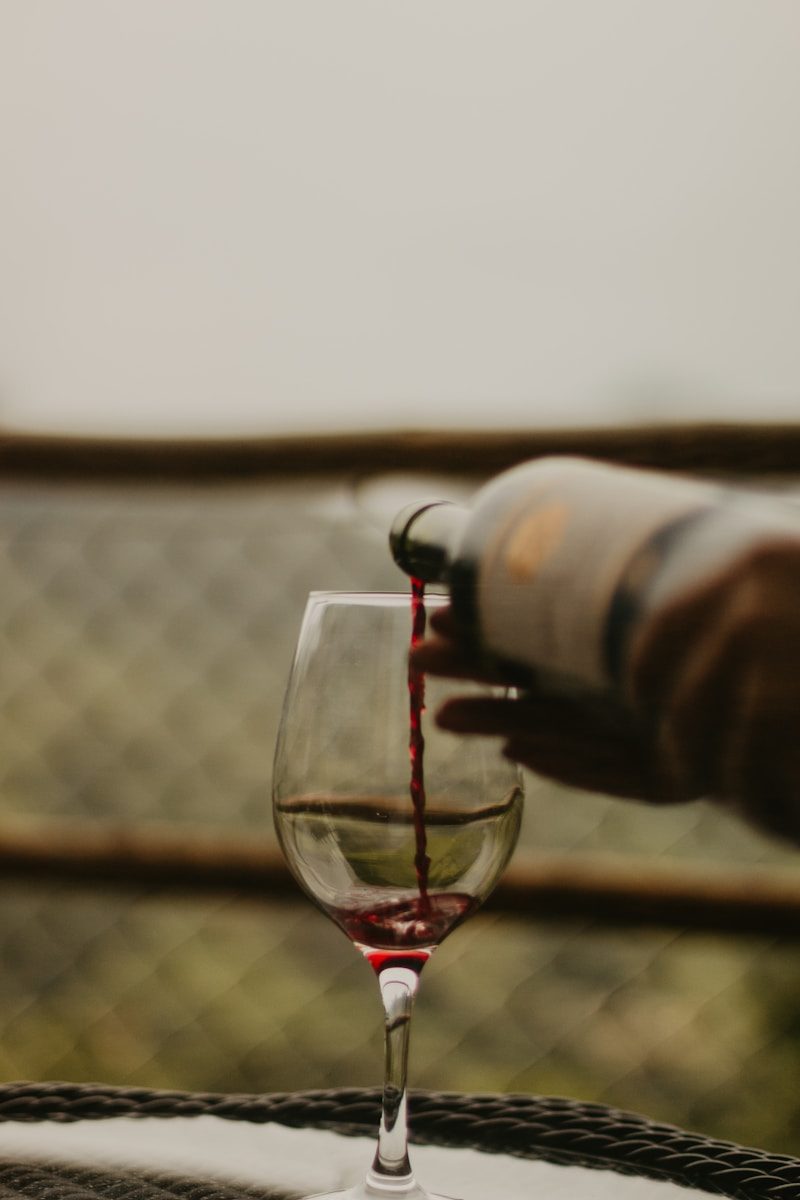 a person pours red wine into a wine glass